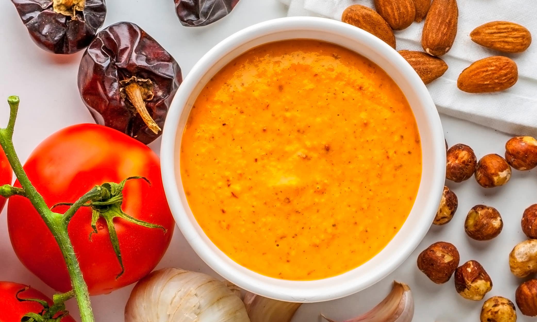 Romesco sauce is typically prepared with ñora peppers, tomatoes, almonds and hazelnuts.