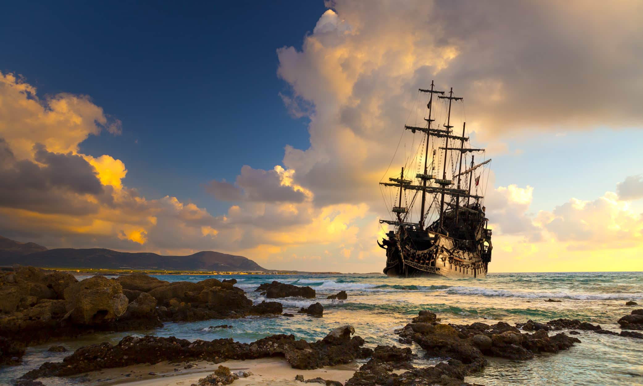 Pirate ship on the open Mediterranean Sea at sunset.