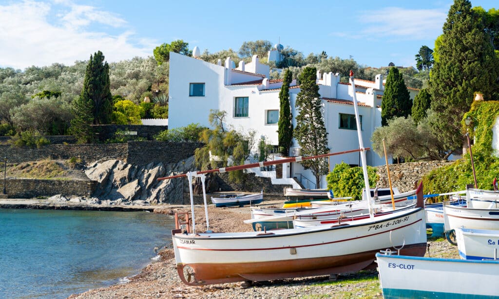 njoy costa brava casa museu dali portlligat Casa-Museu Dalí in Portlligat with traditional fishing boats by the shore.
