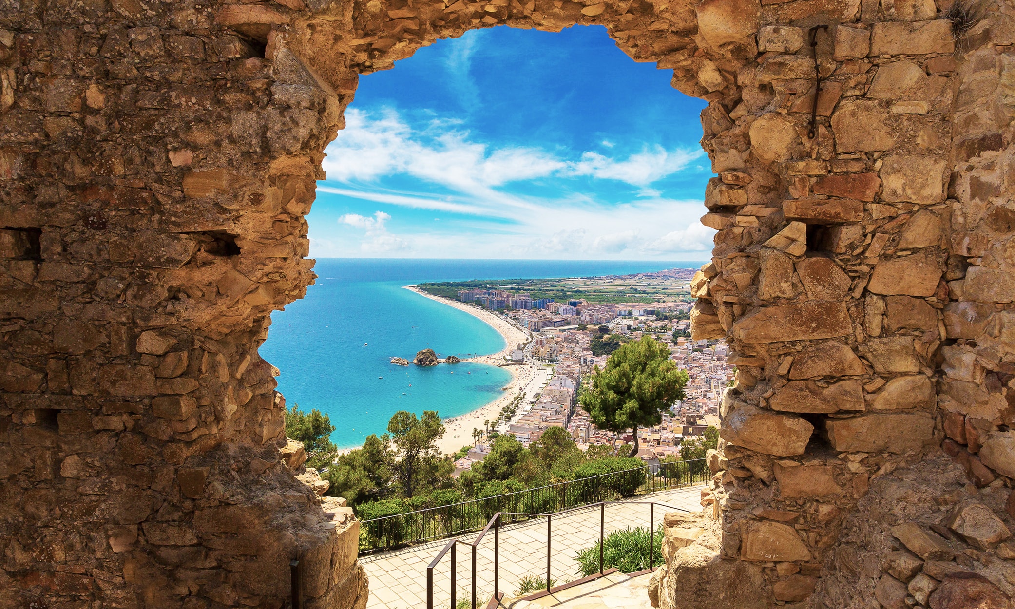 View of Blanes and its coastline from the Castle of San Juan, framed by the ancient stone walls.